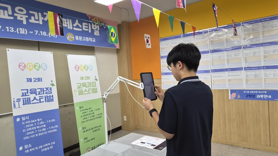 전시된 과목 안내와 디지털 자료를 살펴보는 학생