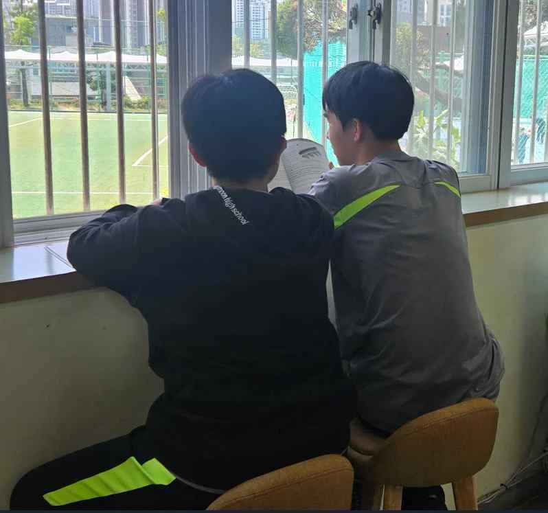 도서관 창가에서 나란히 책을 읽는 학생들