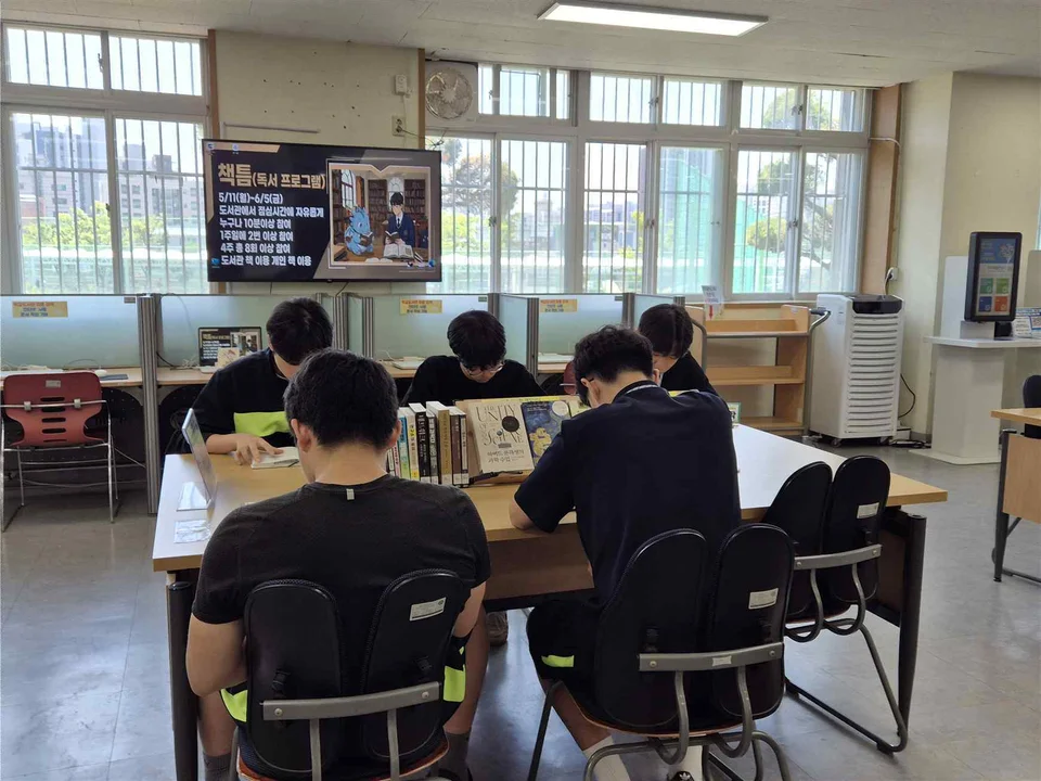 도서관 탁자에 둘러앉아 각자 독서하는 학생들